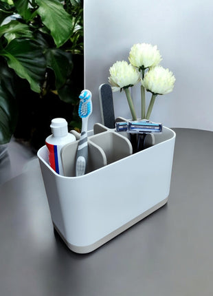 FlexiBox – Modularer Zahnputz - & Badezimmer - Organizer - Print HomeFlexiBox – Modularer Zahnputz - & Badezimmer - Organizer8890878Print Homebad - accessoiresFlexiBox modularer Badezimmer - Organizer in Soft White mit fünf Fächern für Zahnbürsten, Zahnpasta und Rasierer auf einem Beistelltisch neben einer Pflanze.badezimmer - aufbewahrung