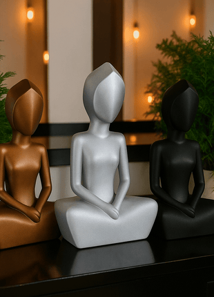 Anmutige Eleganz: Die feminine Frauenskulptur - Print HomeAnmutige Eleganz: Die feminine FrauenskulpturPrint HomeDreier - Set moderner Meditationsskulpturen in den Farben Bronze/Kupfer, glänzendem Silber und mattem Schwarz, arrangiert zwischen Zimmerpflanzen.